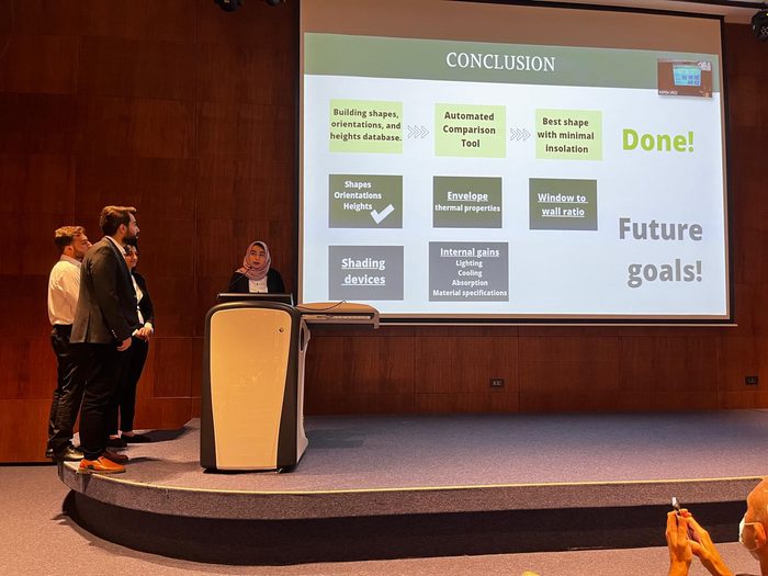 Team presenting on stage in front of a slide titled Conclusion